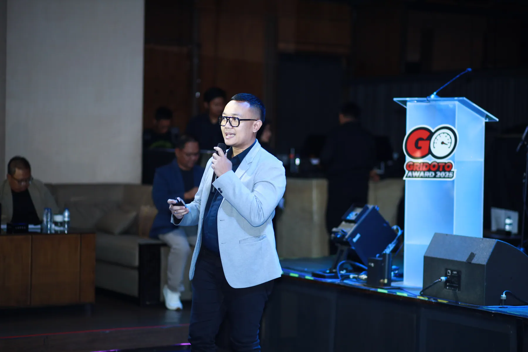 Cahyanto berdiri di sisi panggung sambil berbicara kepada peserta.